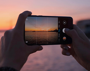 A mobile phone taking a picture of a beautiful sunset.