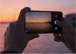 A mobile phone taking a picture of a beautiful sunset.